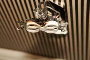 A Burnt Electrical Outlet With Exposed Wires And Damage Is Mounted On A Striped Wall.