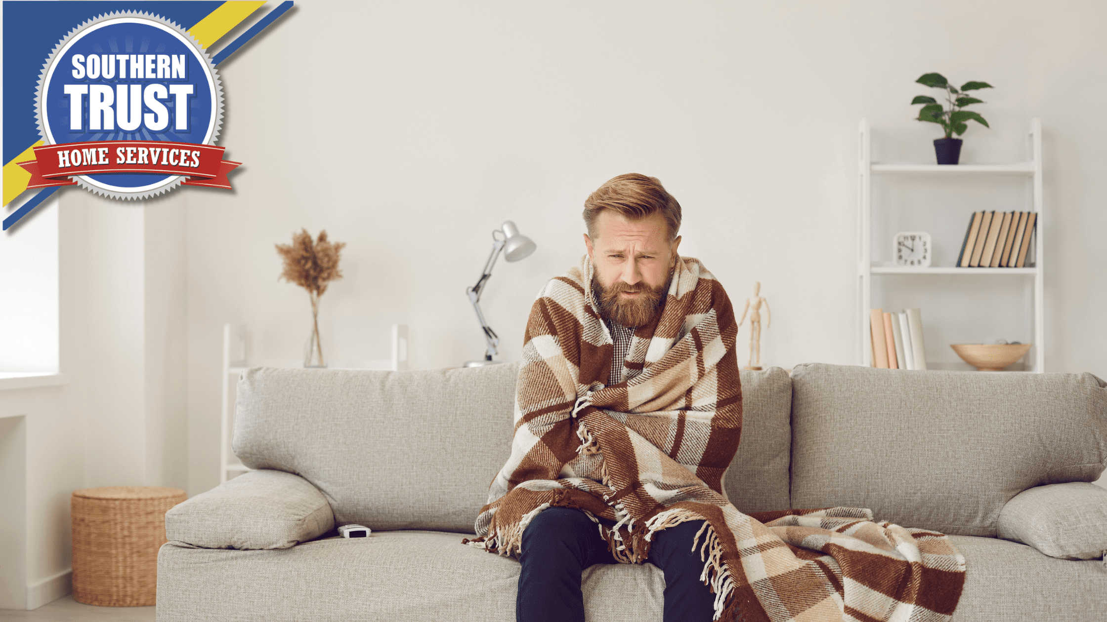 A man sitting on a sofa wrapped in a plaid blanket, looking cold. There is a logo for Southern Trust Home Services in the top left corner.