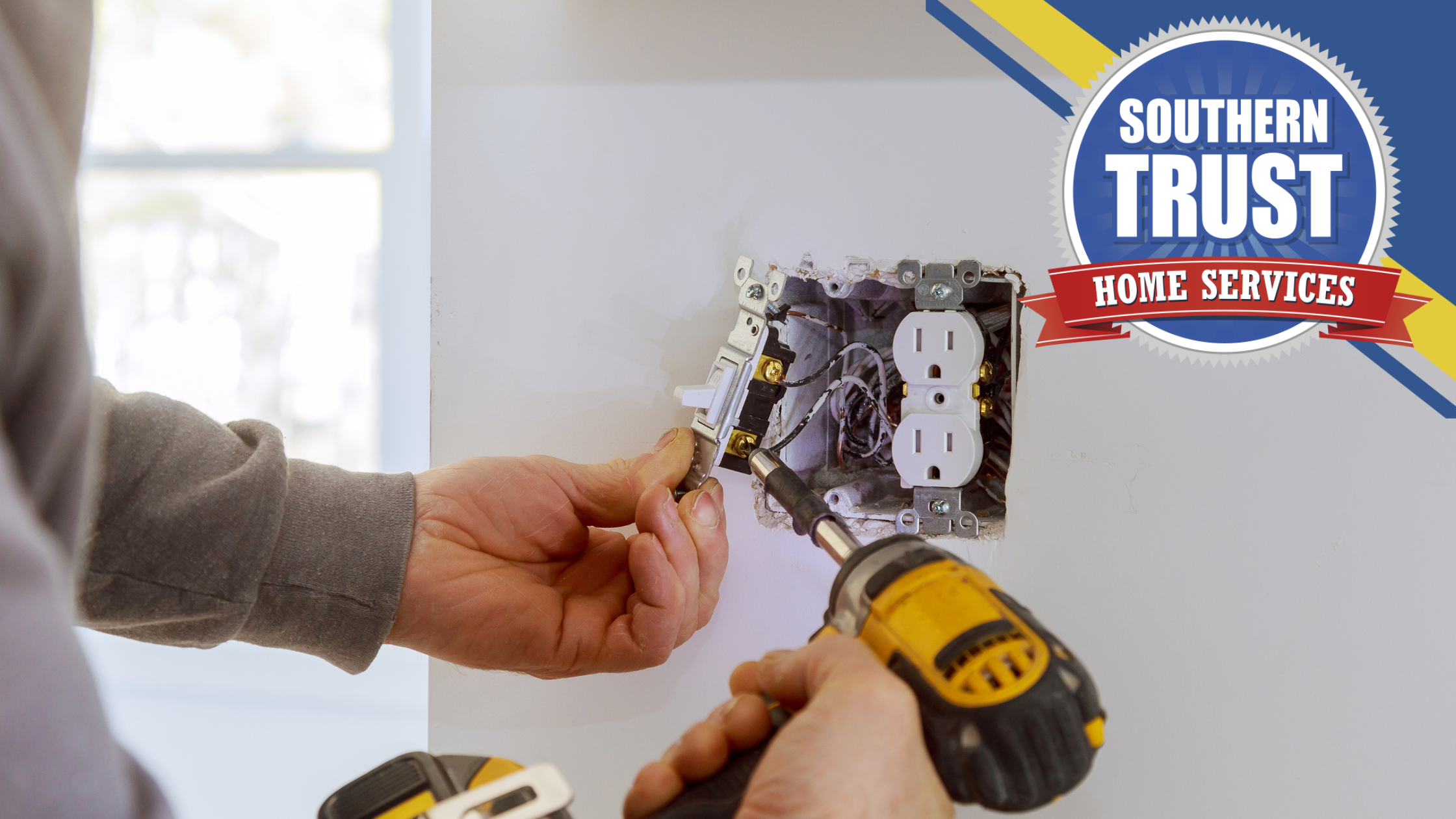 Person using a screwdriver to install or repair a wall electrical outlet with a Southern Trust Home Services logo in the corner.