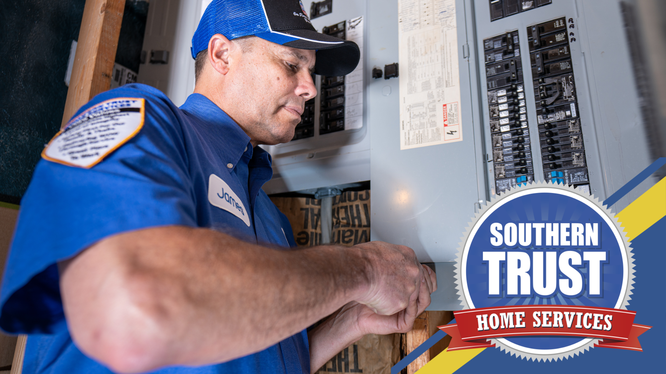 Electrician in blue uniform working on a circuit breaker panel. Logo on the image reads: "Southern Trust Home Services".