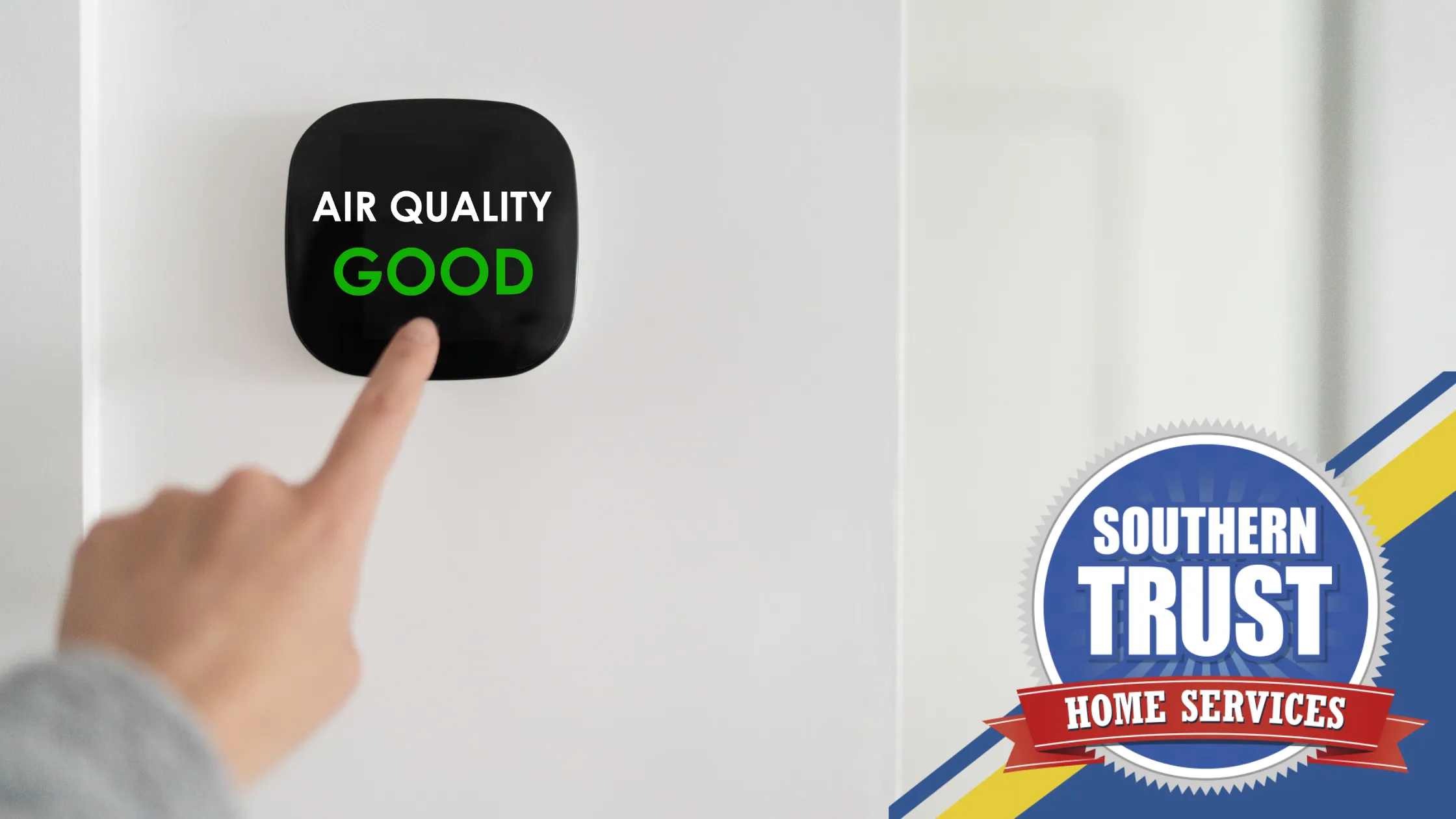A person points at a wall-mounted device displaying "Air Quality Good." Southern Trust Home Services logo is visible in the bottom right corner.