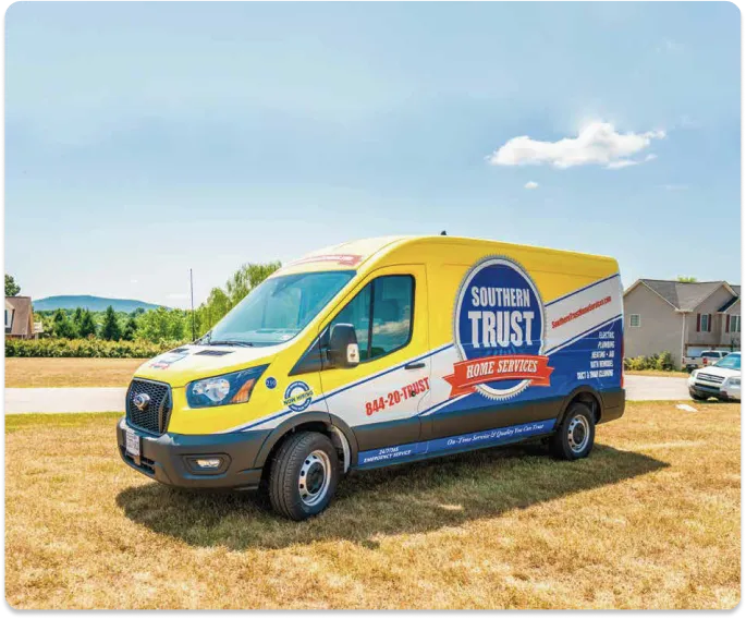 A Yellow And Blue Service Van Parked On A Grassy Area Beside A Road, With Trees And A House In The Background. The Van Is Branded &Quot;Southern Trust Home Services.